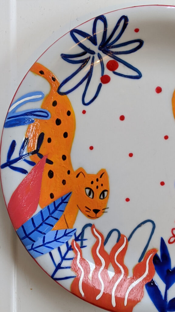 Hand-painted ceramic plate featuring a tiger hidden among tropical plants.